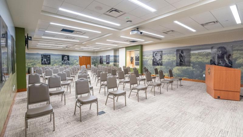 的 苹果溪会议室 setup for a presentation features wet-plate photos of Native Americans overlaying a wall wrap of the Missouri River Valley.