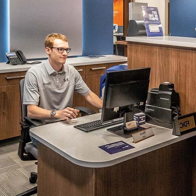 Business student at desk working on computer at the on campus bank